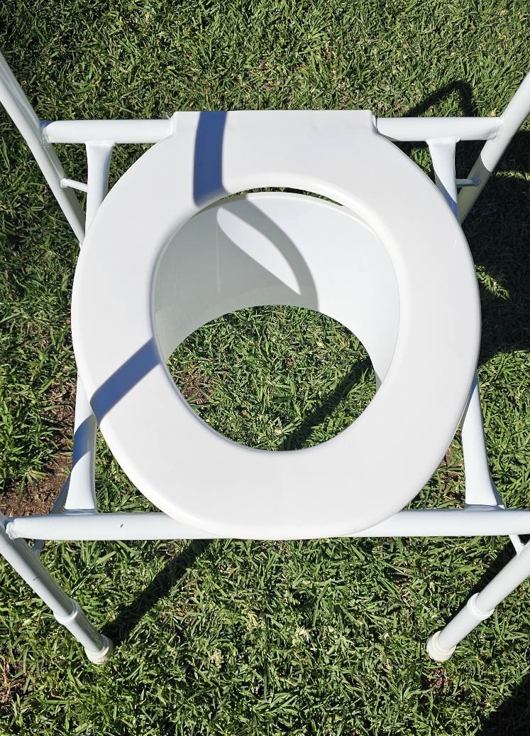 Portable raised toilet seat with blue support straps on a lightweight metal frame, shown outdoors to display condition